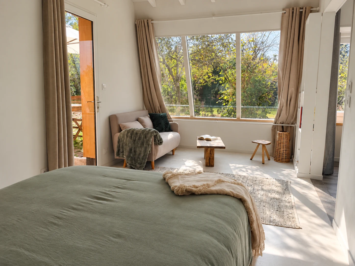 Depuis la chambre, le regard s’ouvre directement sur le jardin , avec un canapé convertible offrant un couchage supplémentaire.